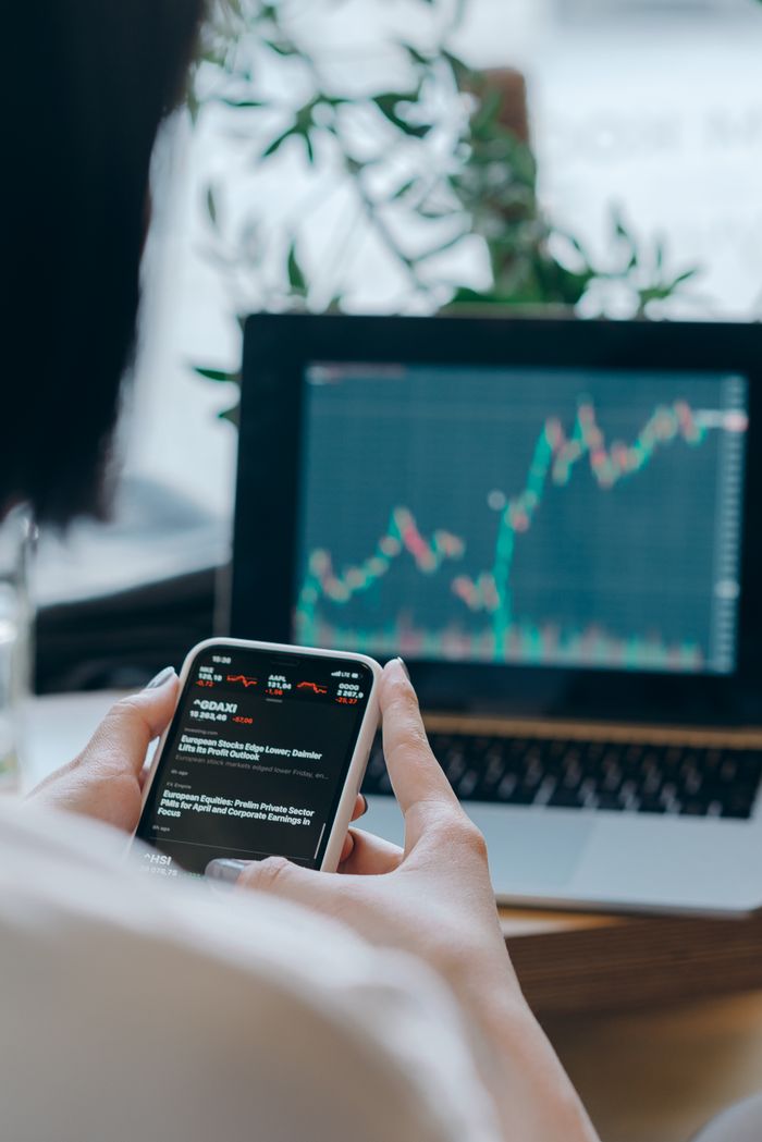 The Art of Drawing Readers In: Your attractive post title goes here Person using smartphone for stock market analysis at home office.